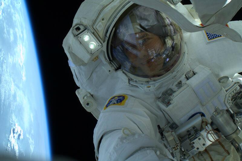 Астронавт Том Машберн смотрит на Землю во время выхода в открытый космос